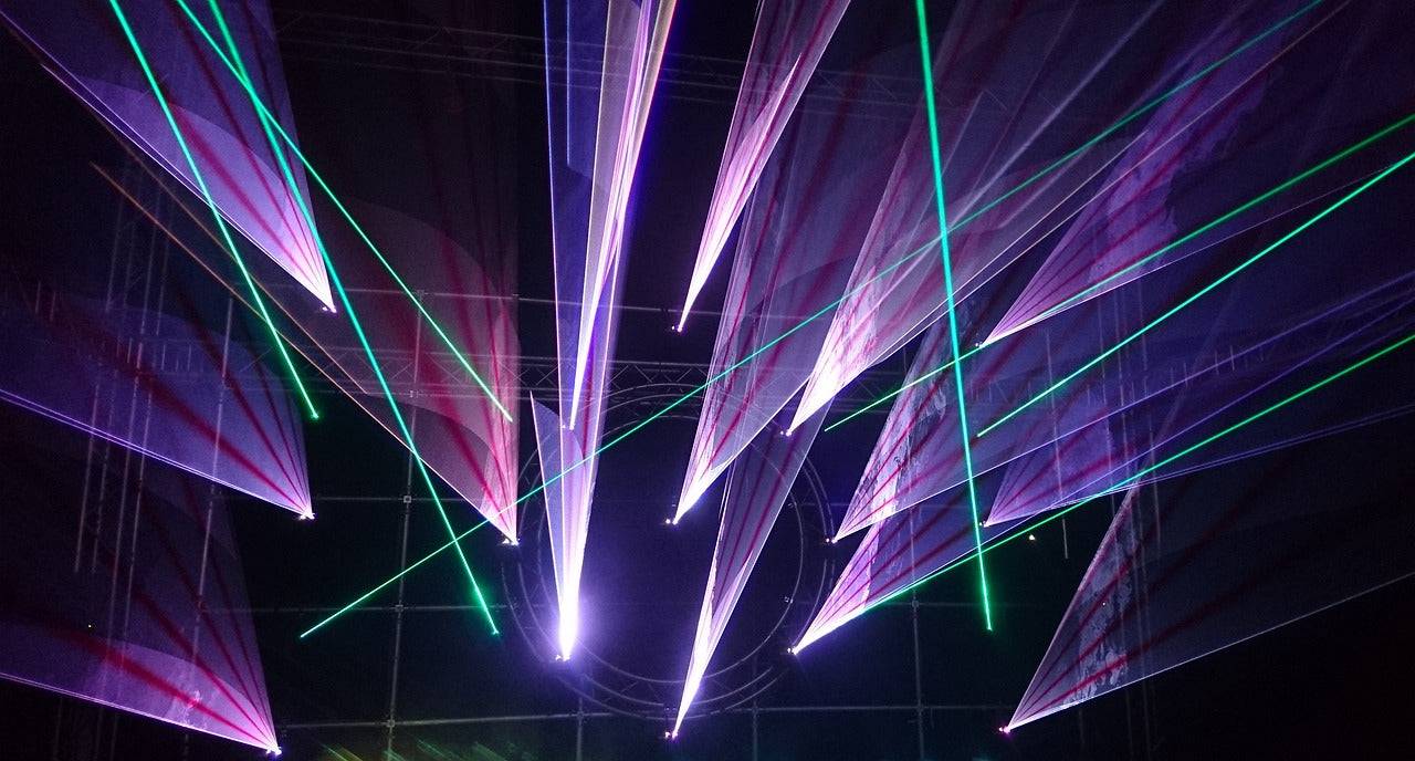 Bunte Lasershow mit violetten und grünen Strahlen – symbolisiert VisionX Meditation für kreative Impulse und bewusstseinserweiternde Erlebnisse.